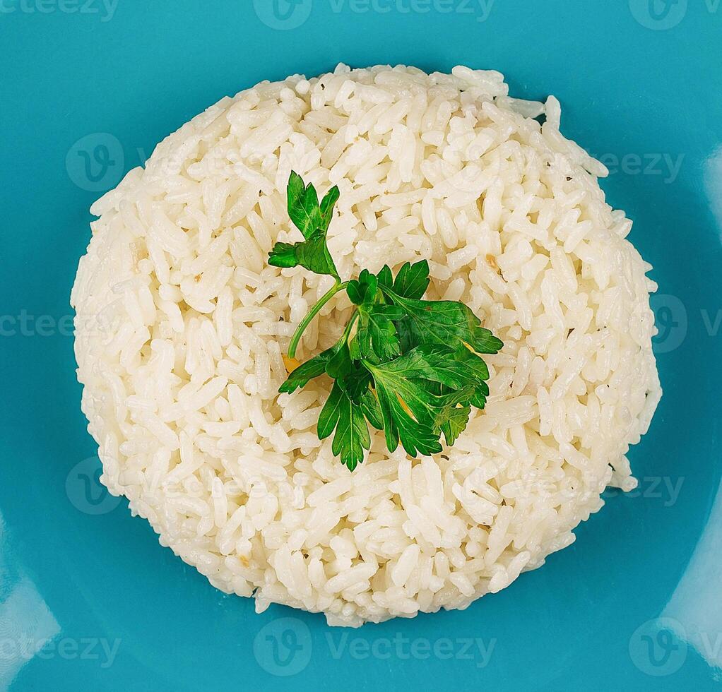 Steamed white rice lying on blue plate with parsley garnish photo