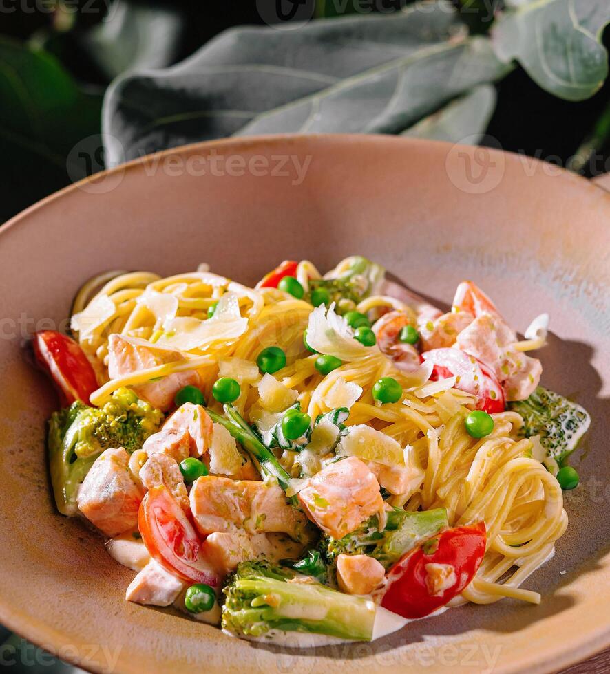 Salmon pasta dish with green peas and parmesan cheese on restaurant table photo