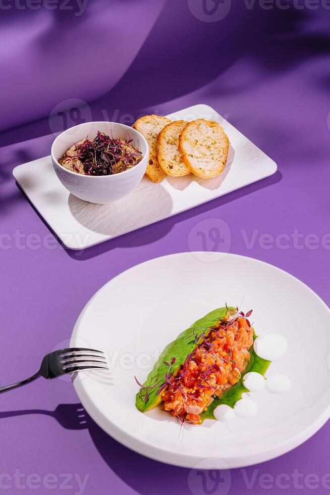 Gourmet dishes with salmon tartare and toasts on purple background photo