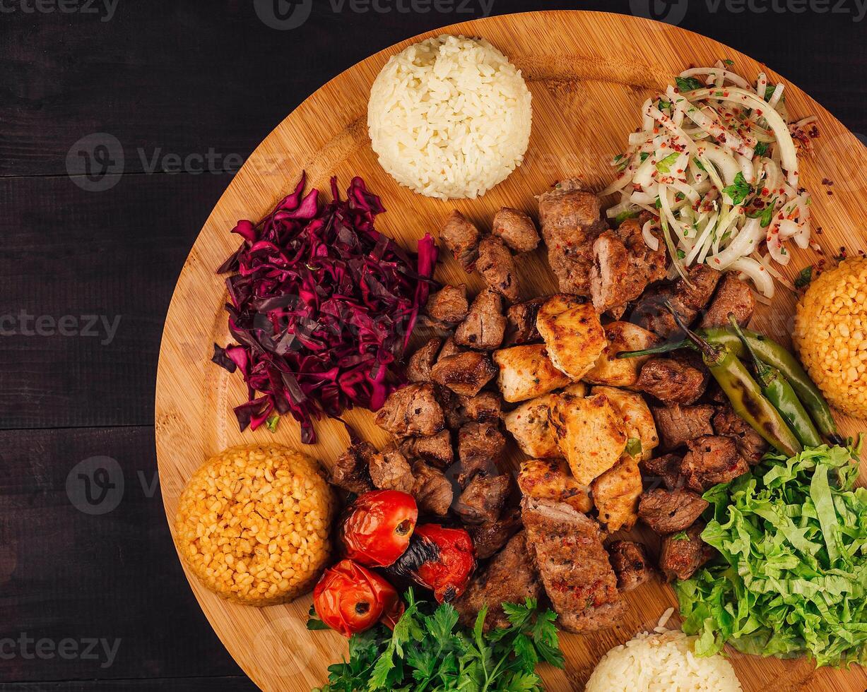 Turkish kebab serving with rice and vegetables on wooden plate photo