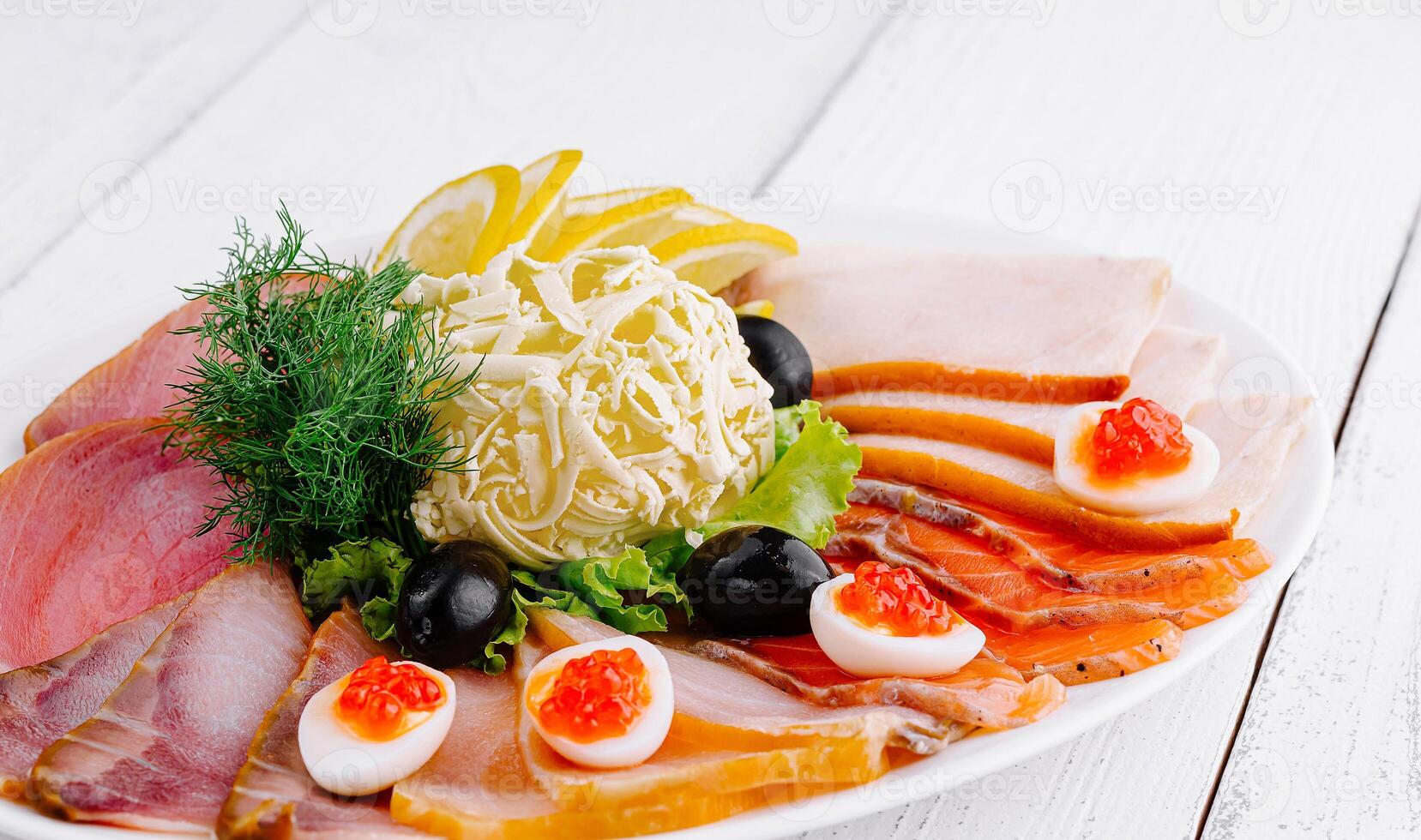 Delicious sliced fish platter with butter lemon and olives on white table photo