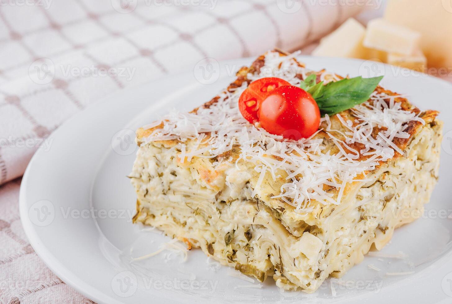 Slice of vegetarian lasagna garnished with fresh ingredients on white plate photo