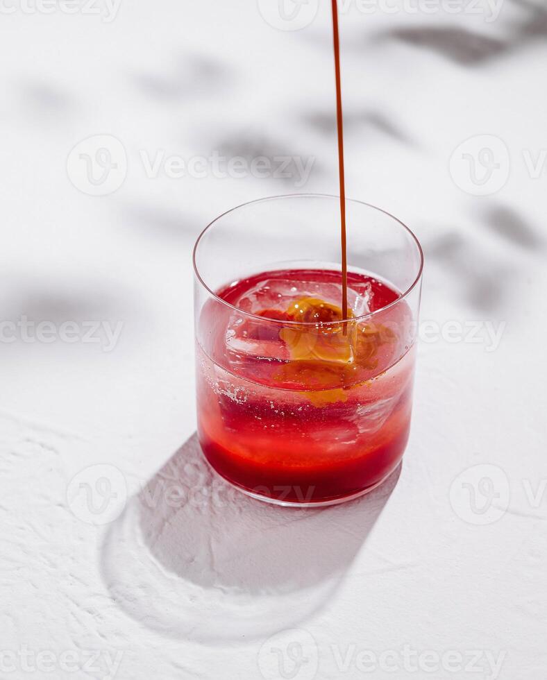 Bartender pouring syrup into cocktail with ice on white background photo