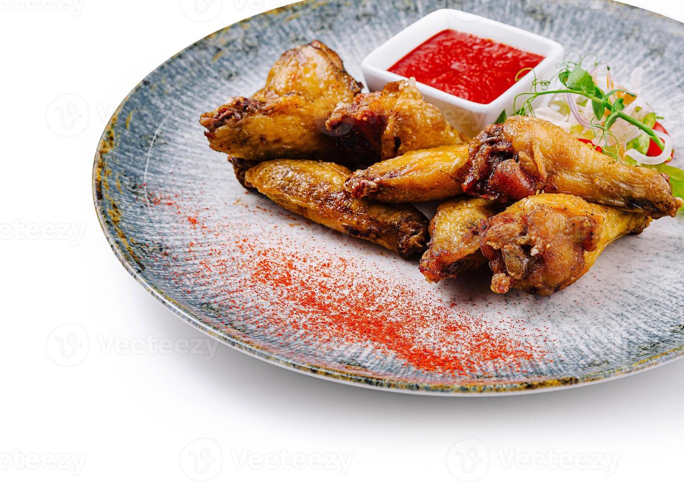 Crispy chicken wings served on modern plate with dipping sauce and garnish photo