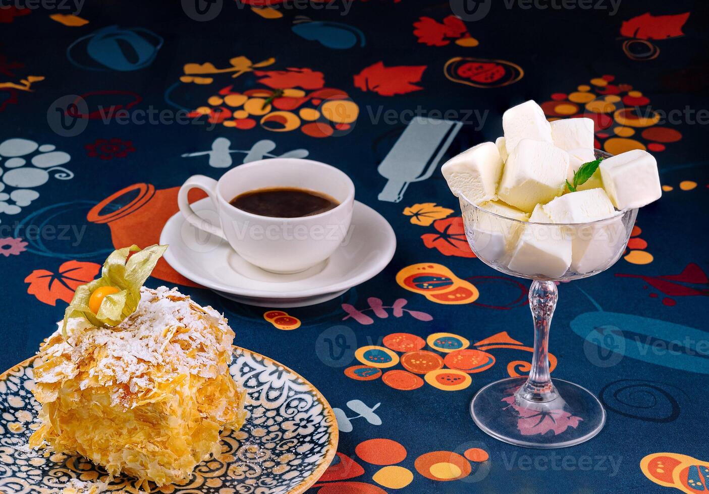 Enjoying delicious napoleon cake with coffee and marshmallows on colorful tablecloth photo
