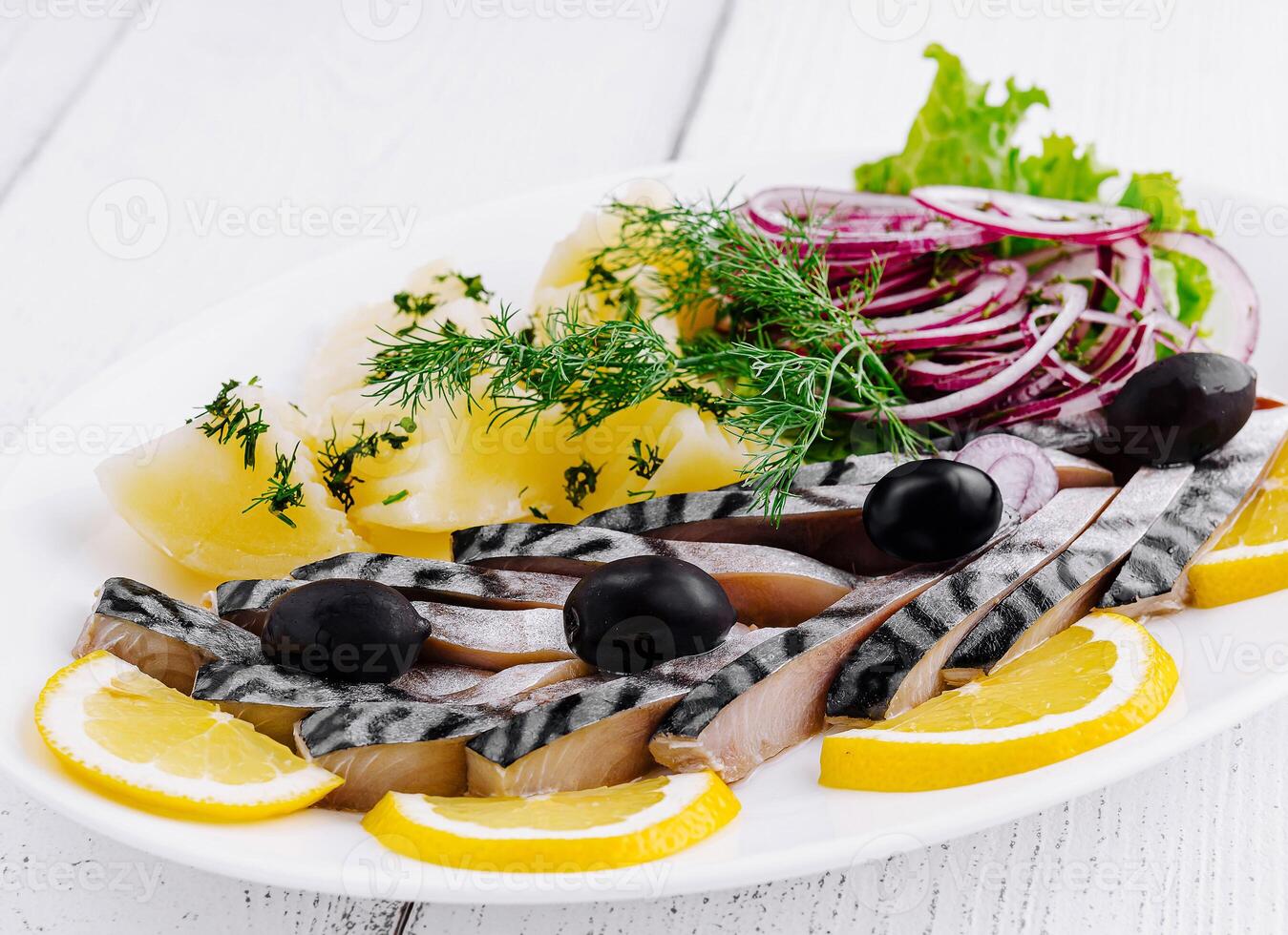 Sliced salted mackerel with potatoes and onions on white plate photo