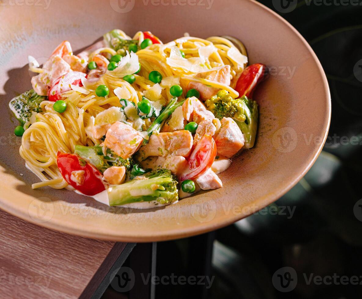 Salmon pasta dish with green peas and parmesan cheese on restaurant table photo