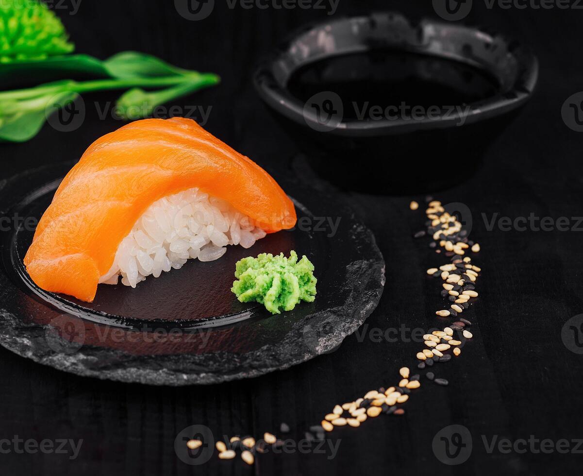 Salmon nigiri sushi with wasabi and soy sauce on black stone plate photo