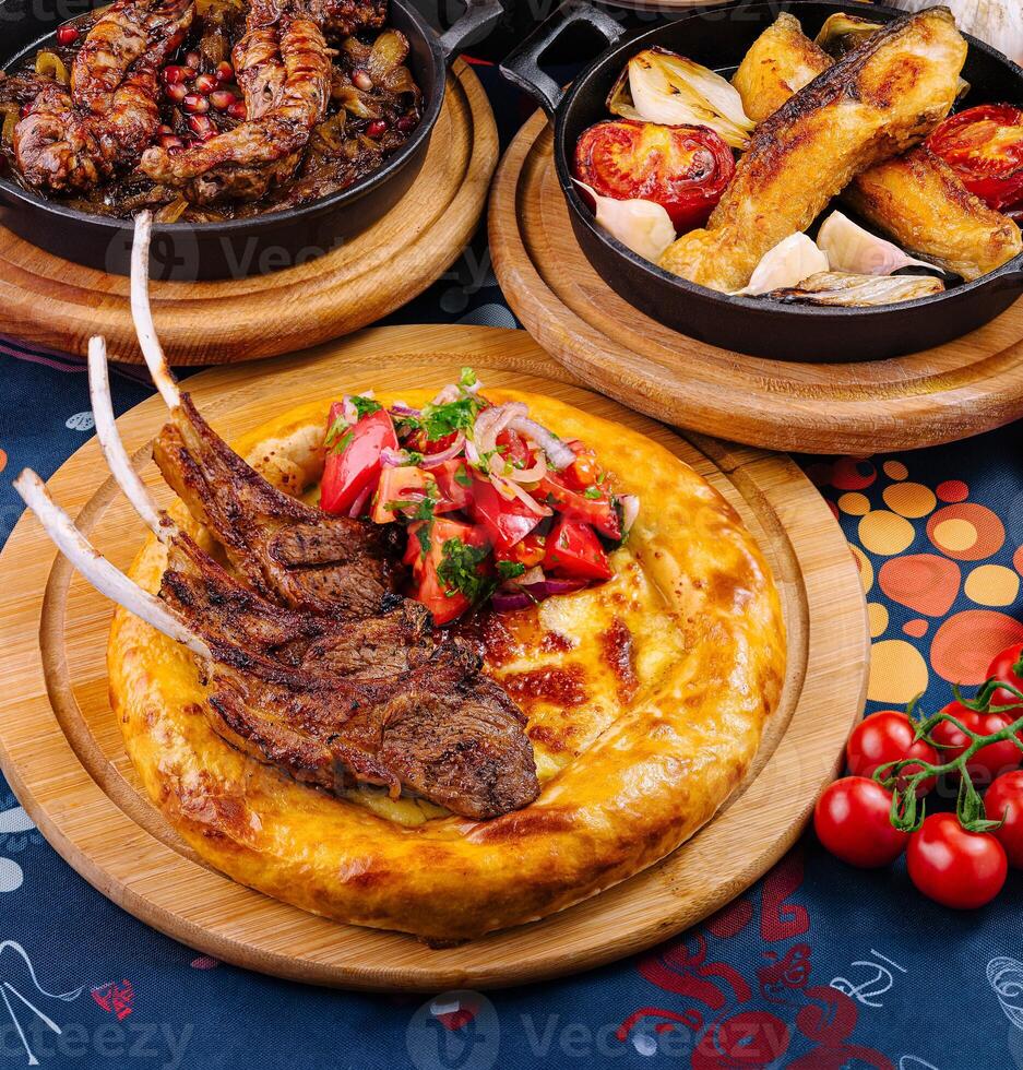 Grilled lamb ribs served on flatbread with salad on restaurant table photo