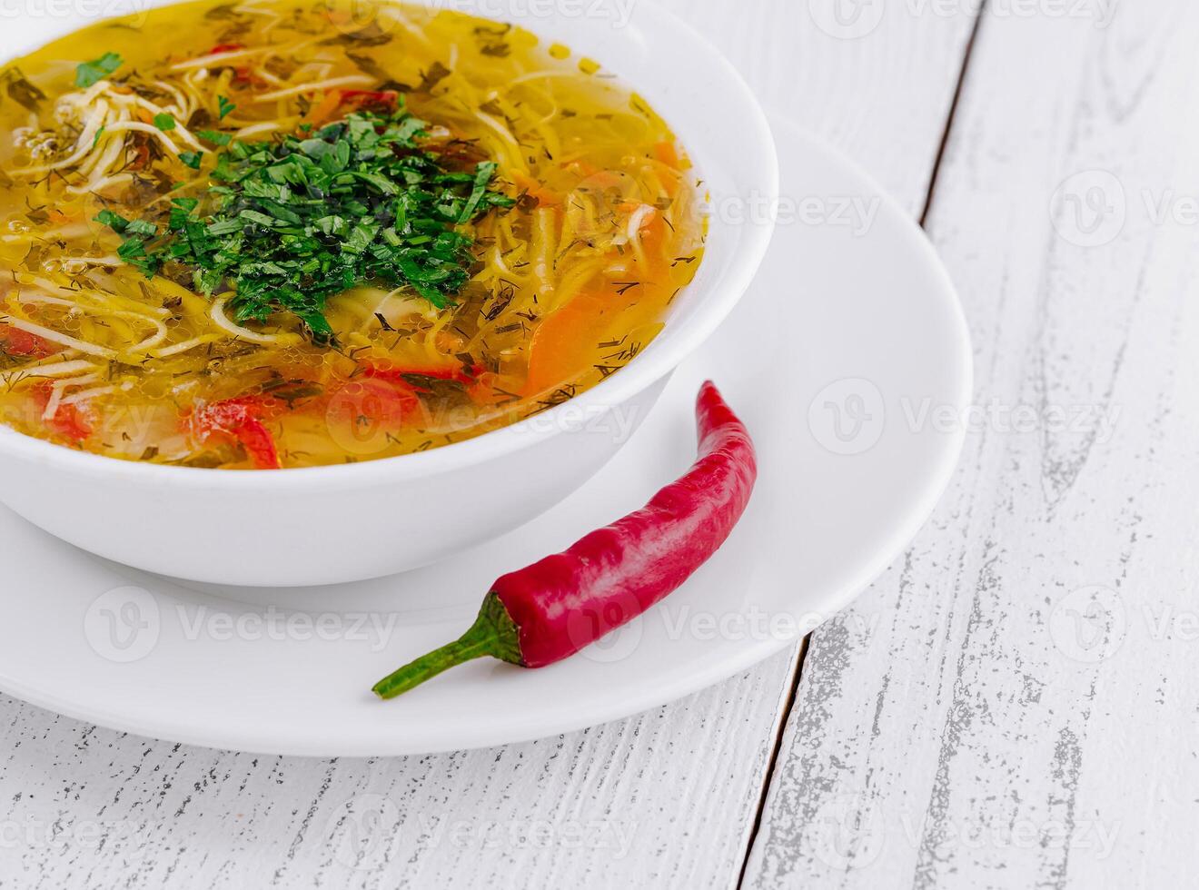 Steaming hot bowl of chicken noodle soup with herbs and spices photo