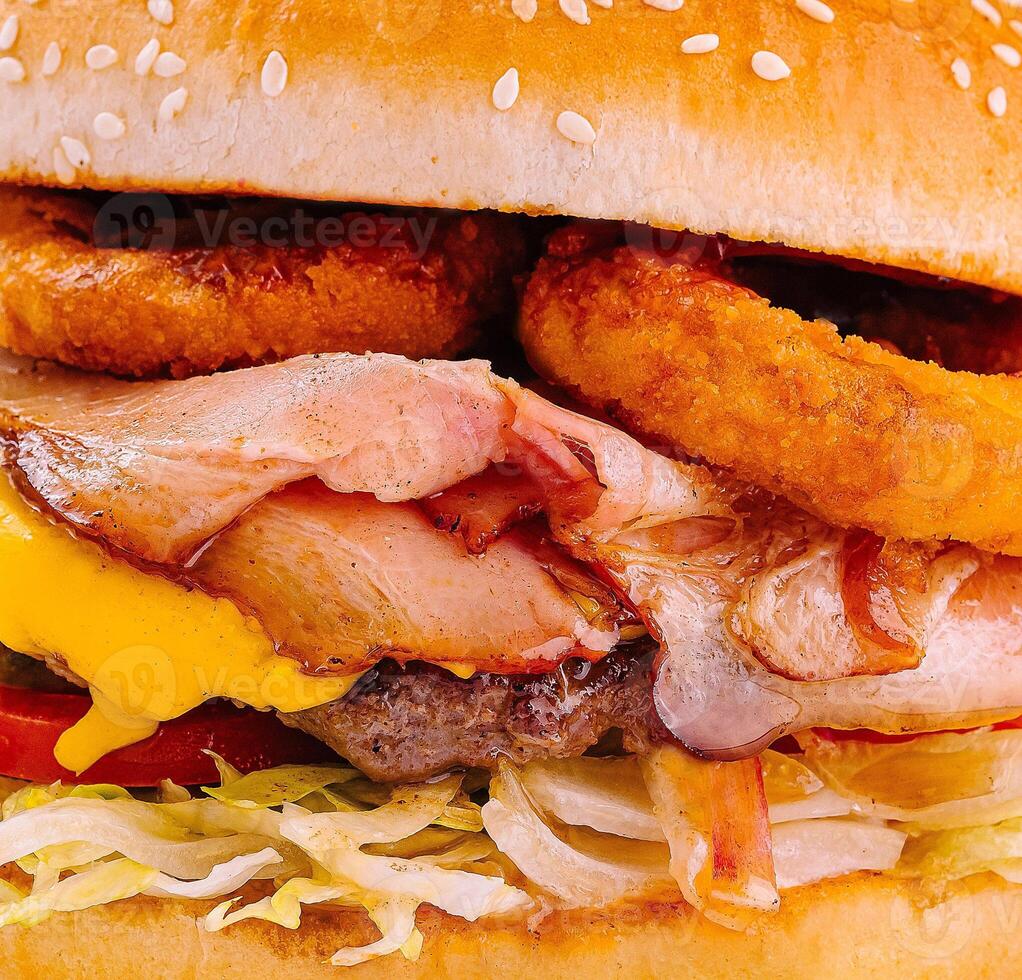 Delicious bacon and onion rings cheeseburger close up photo
