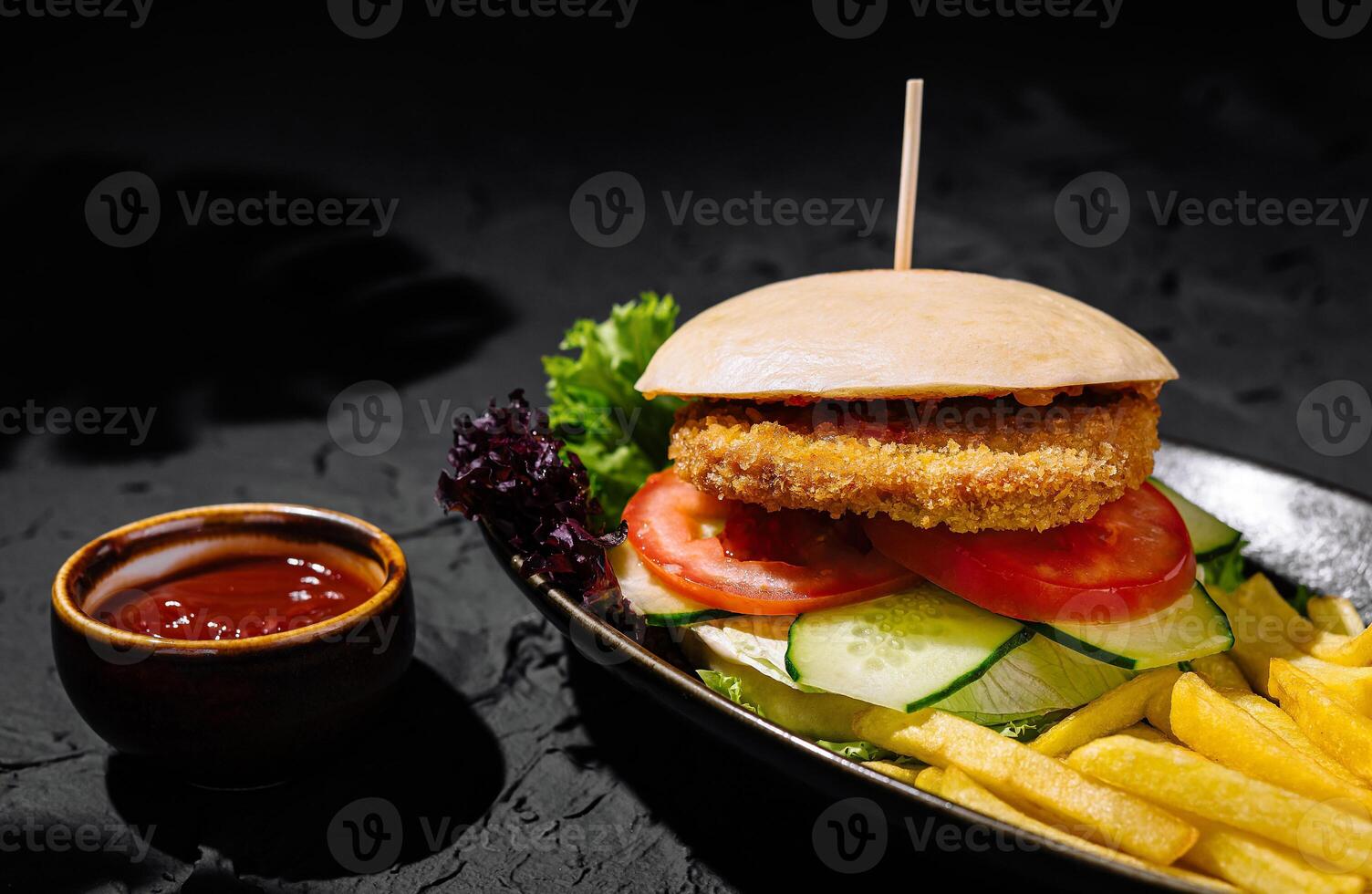 Gourmet chicken burger with fries on dark background photo