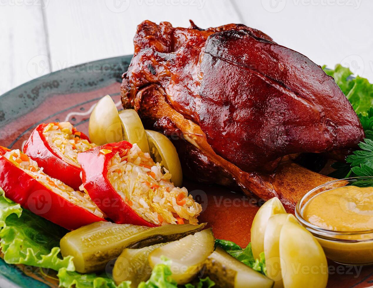 Roasted pork knuckle being served on plate with sauerkraut and mustard photo