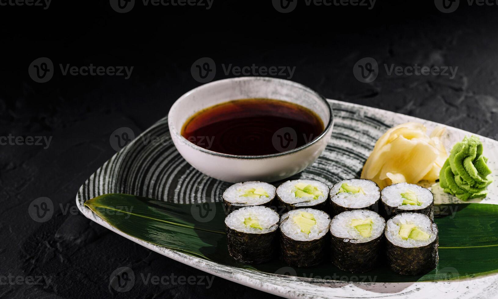 Avocado maki sushi rolls served on elegant plate with soy sauce and wasabi photo