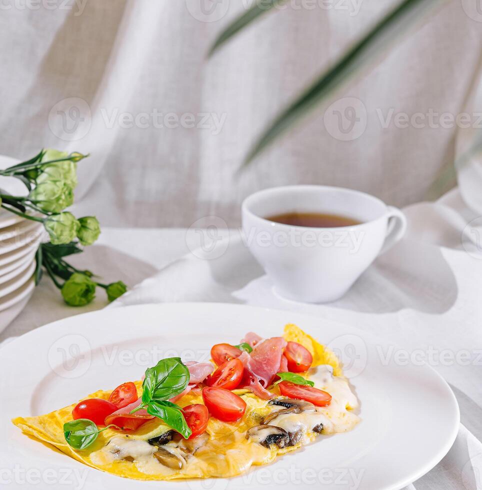Delicious omelette with tomatoes, mushrooms, basil and ham for breakfast photo