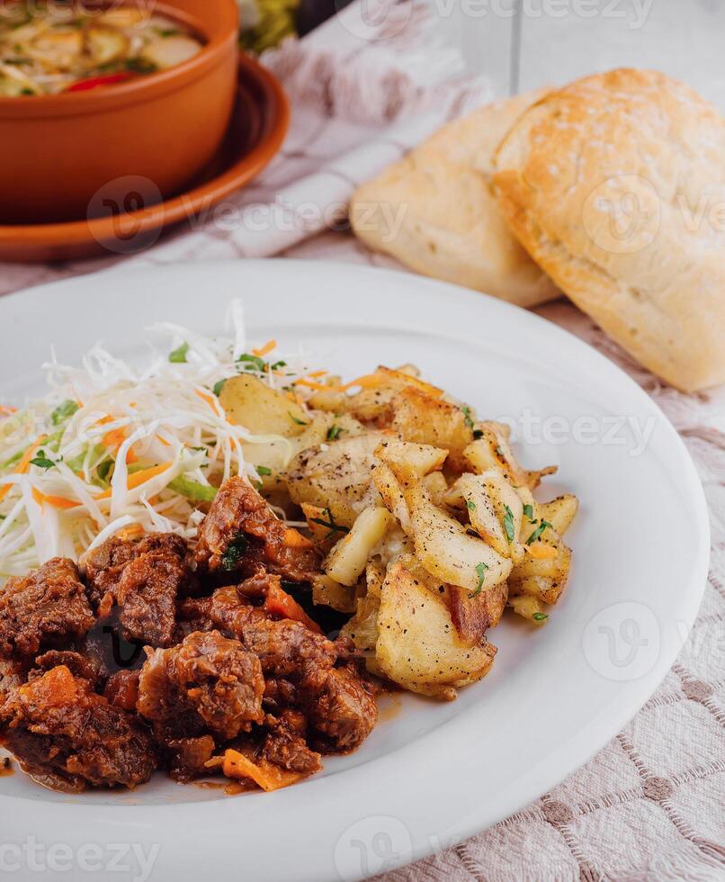 Delicious beef stew served with roasted potatoes and fresh coleslaw salad photo