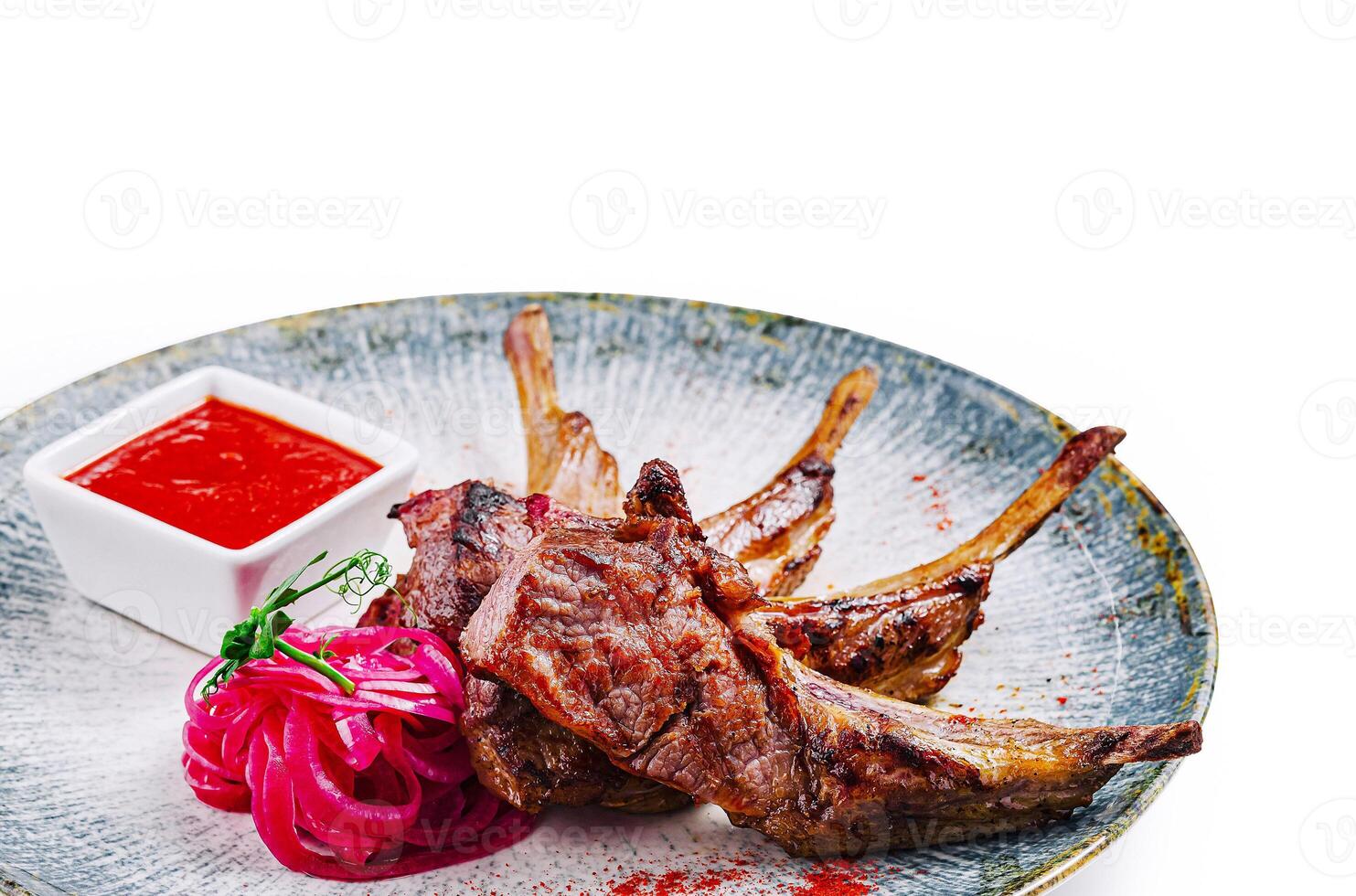 Grilled lamb ribs with red sauce, onion and herbs on plate photo