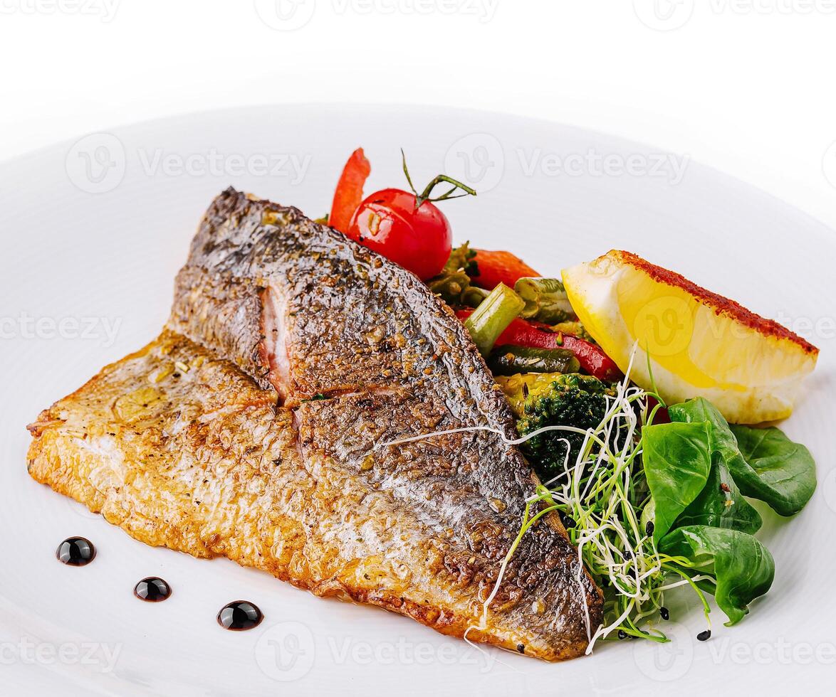 Delicious grilled fish with vegetables and lemon on white plate photo