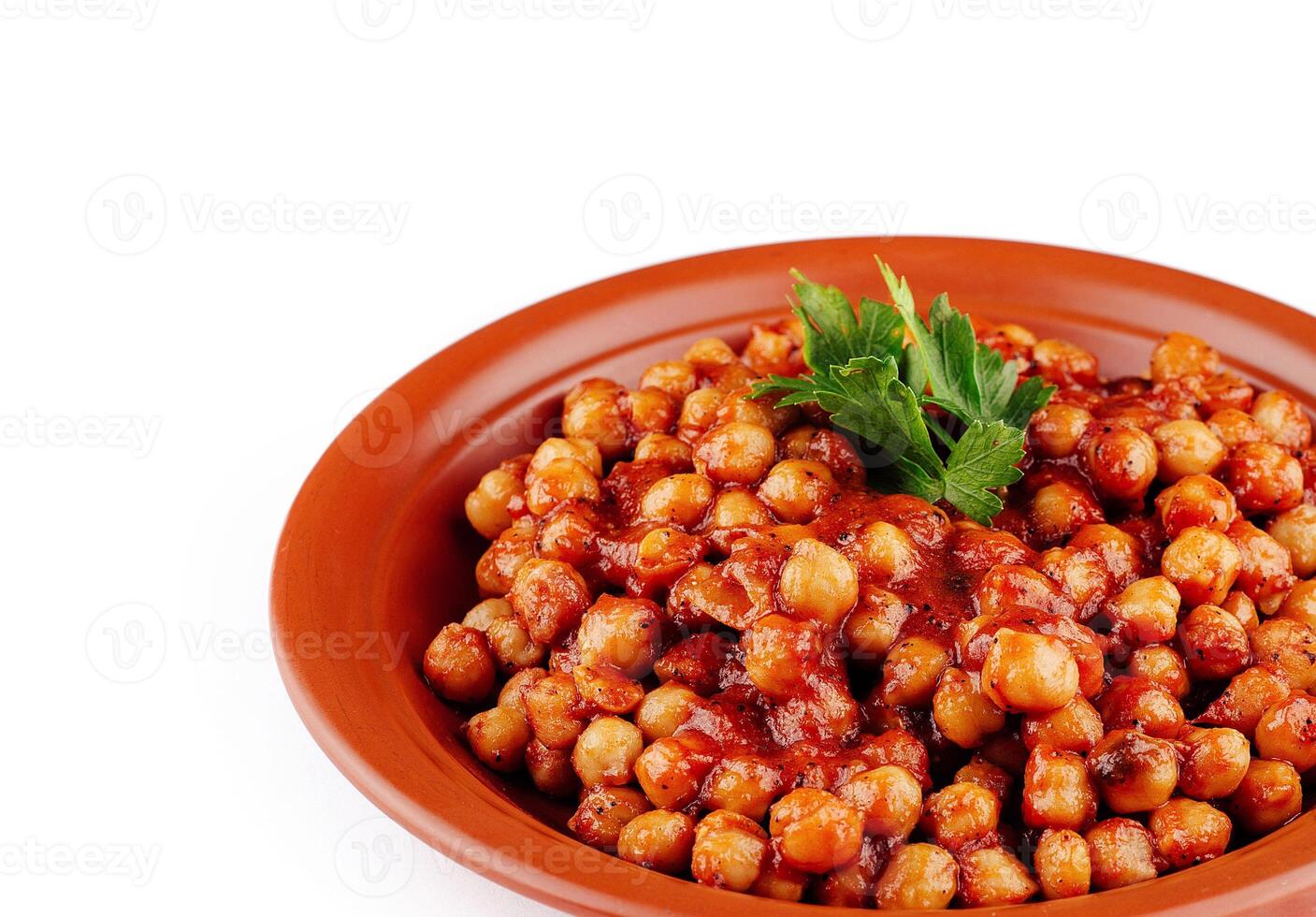Chickpeas lying on plate covered in tomato sauce garnished with parsley photo