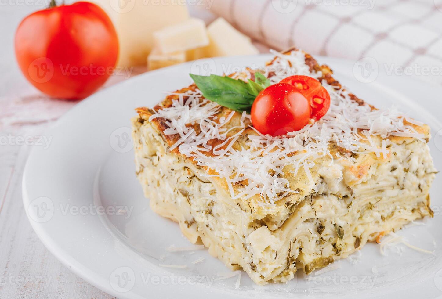 Slice of vegetarian lasagna garnished with fresh ingredients on white plate photo
