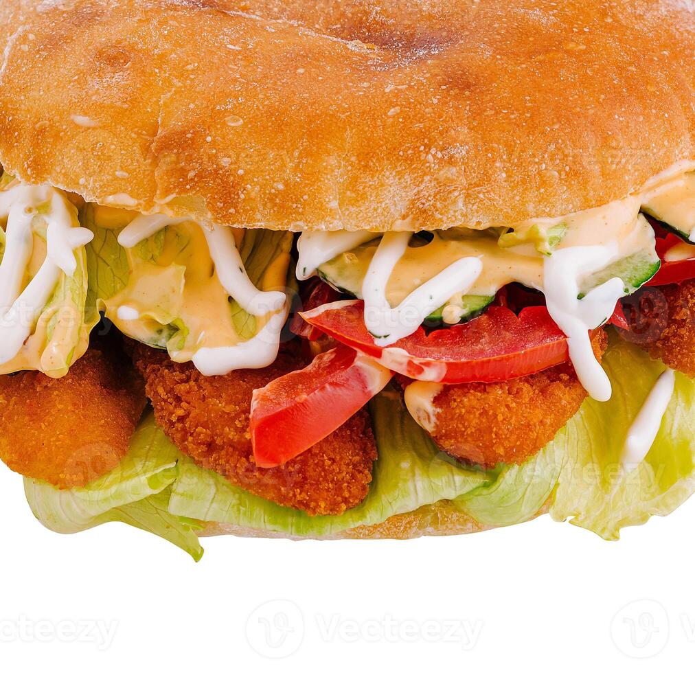 Delicious crispy chicken burger with lettuce, tomatoes and sauce on white background photo