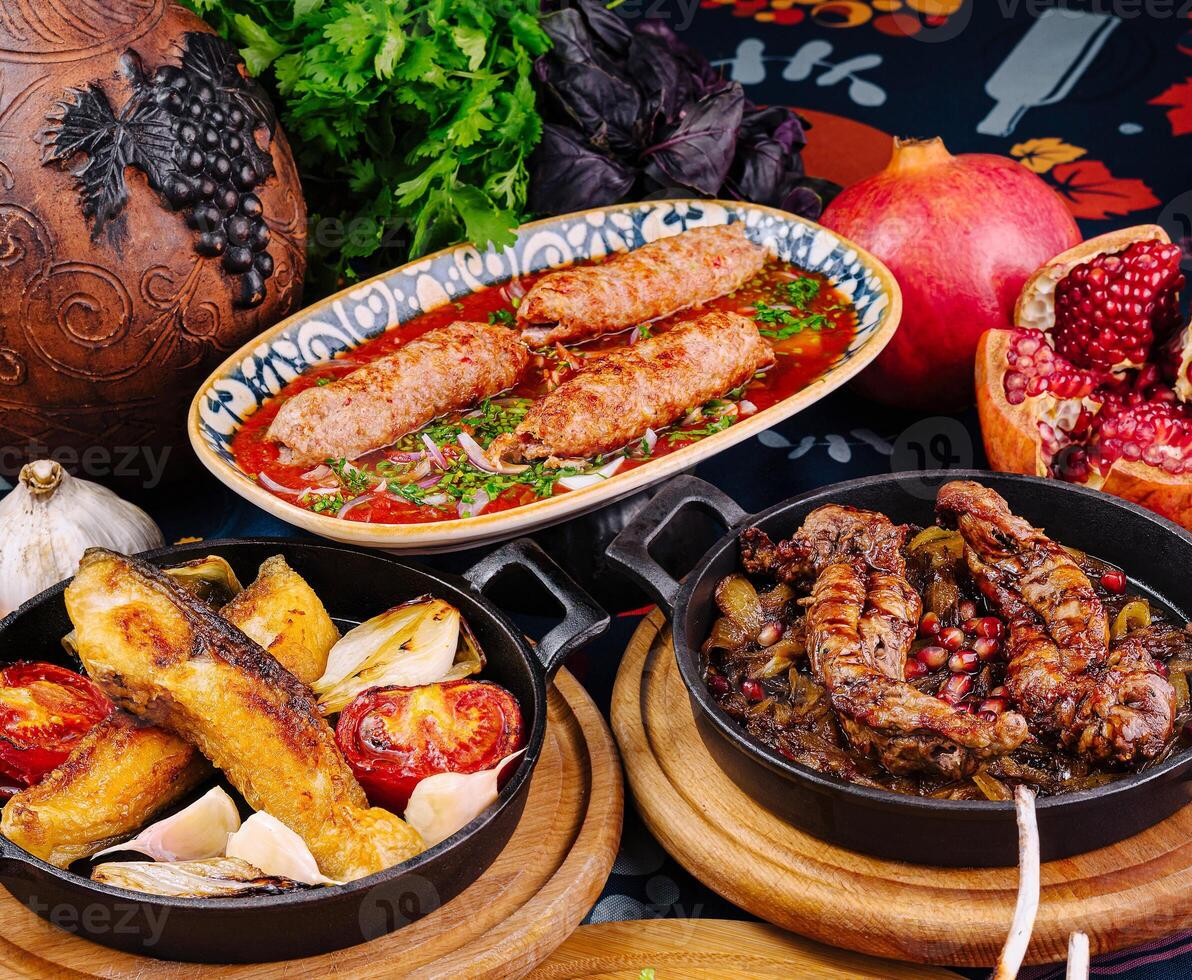 Traditional georgian food on table with lula kebab, grilled fish and meat stew photo