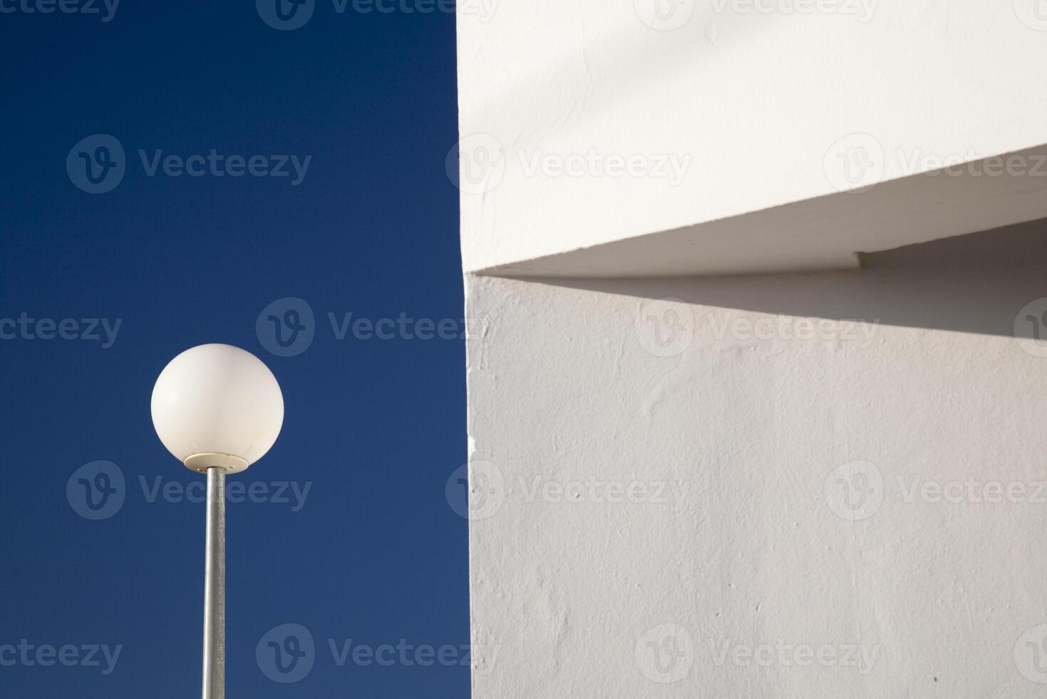 Street Lamp Beside Whitewashed Wall Under Blue Sky in Seville, Spain photo