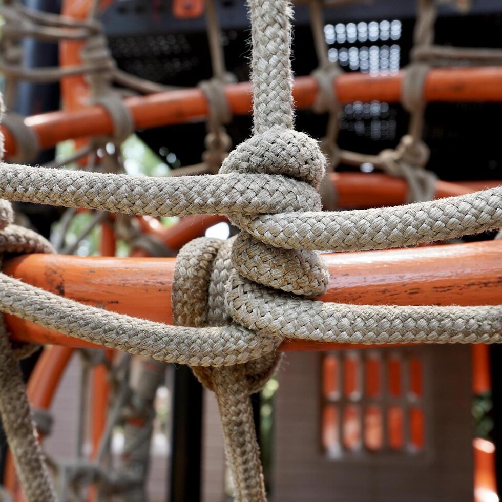Tied up rope knot in outdoor playground toy orange steel bar object background. photo