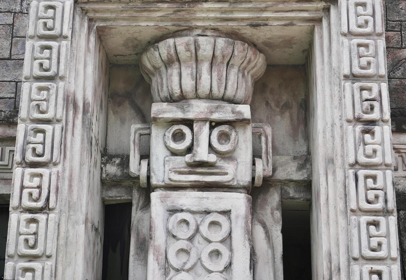 Ancient jungle temple styled rock stone wall statue carving isolated on horizontal building exterior background. photo