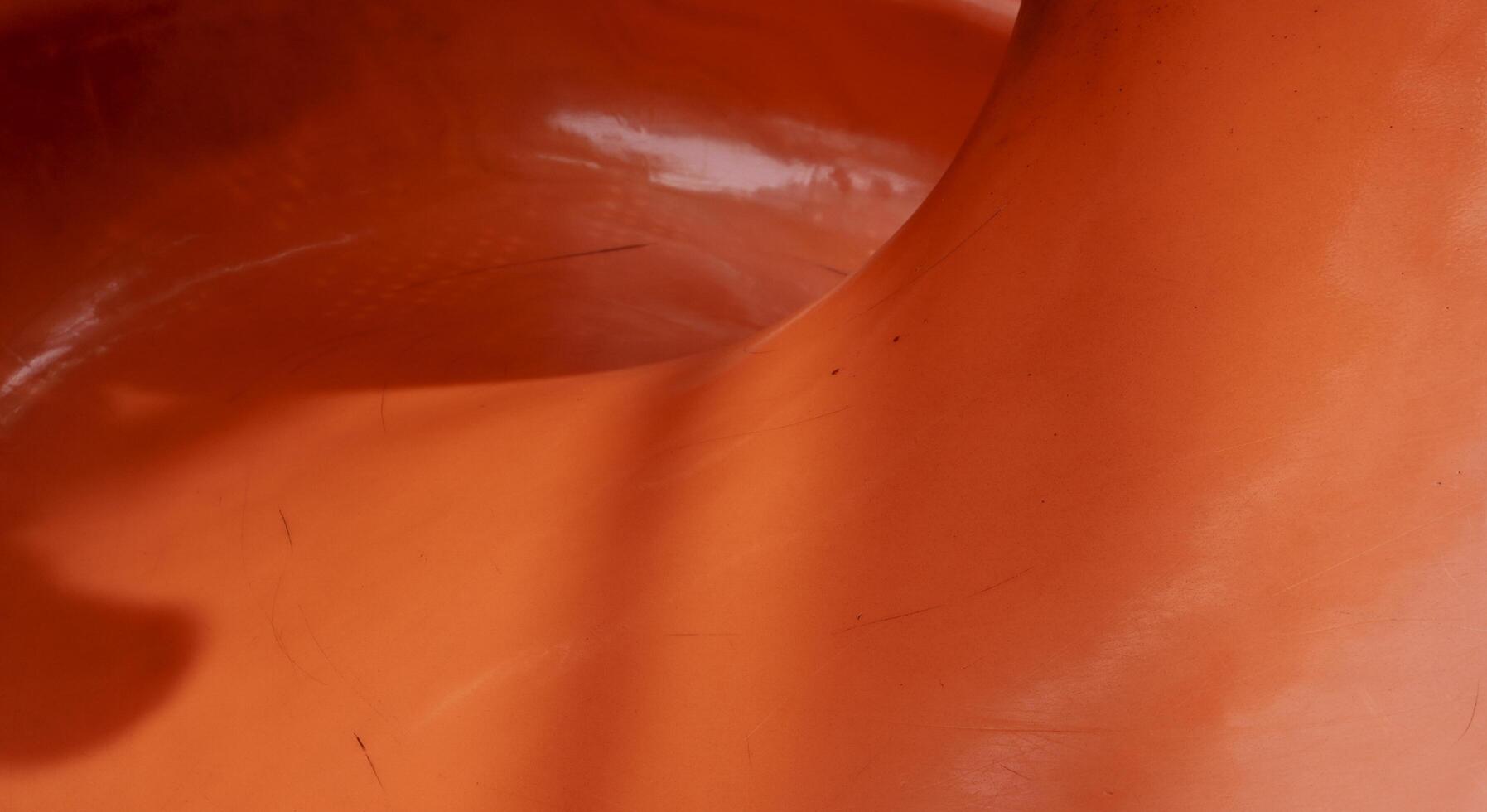 Close up orange plastic playground slide curve turn isolated on horizontal ratio background. photo