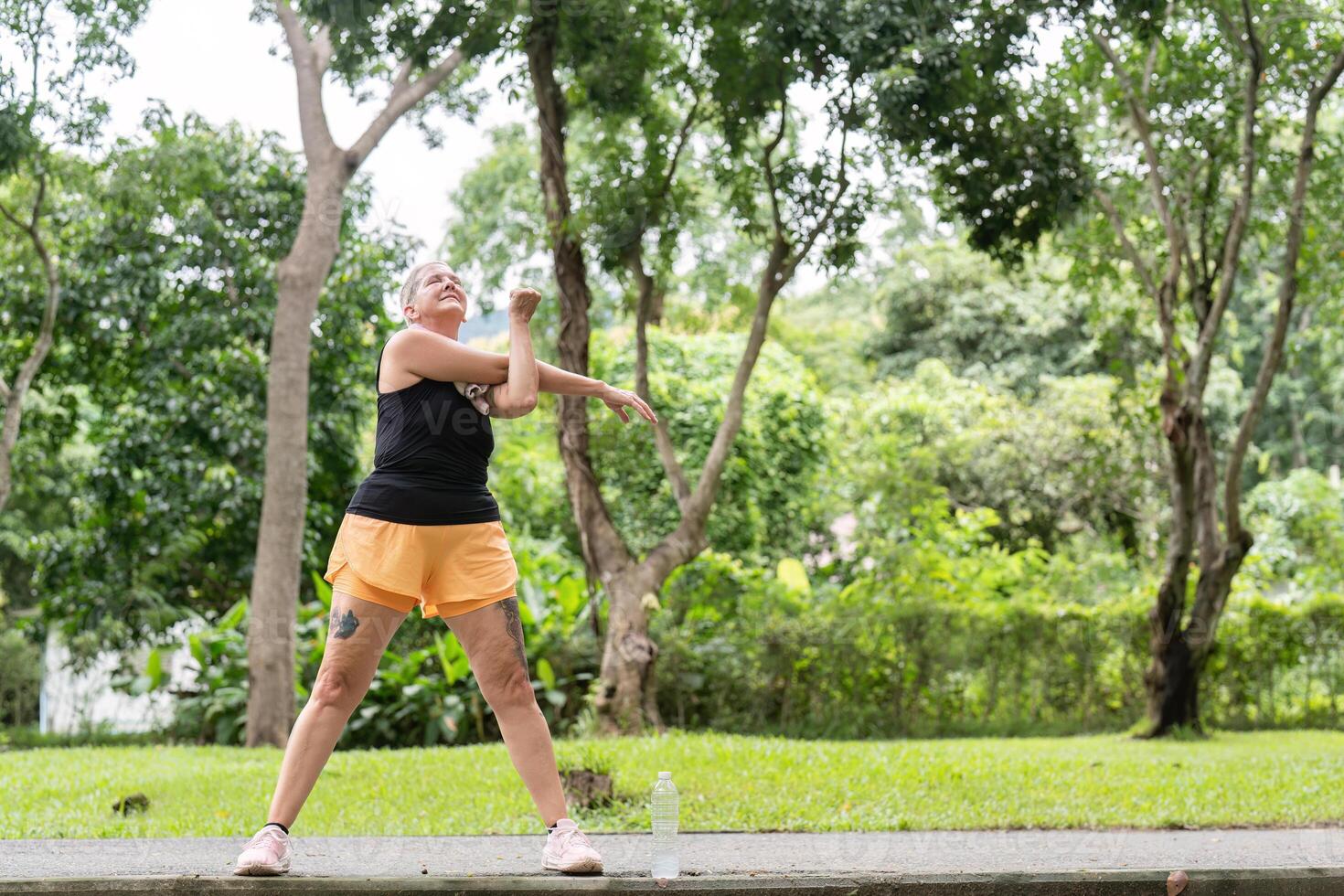 Mature Woman Engaging in Full-Body Stretching for Outdoor Fitness and Health photo