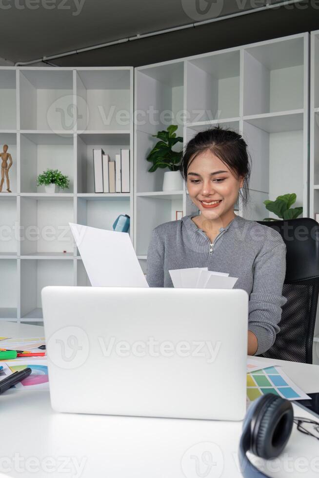 Smiling graphic designer reviewing design drafts in office photo