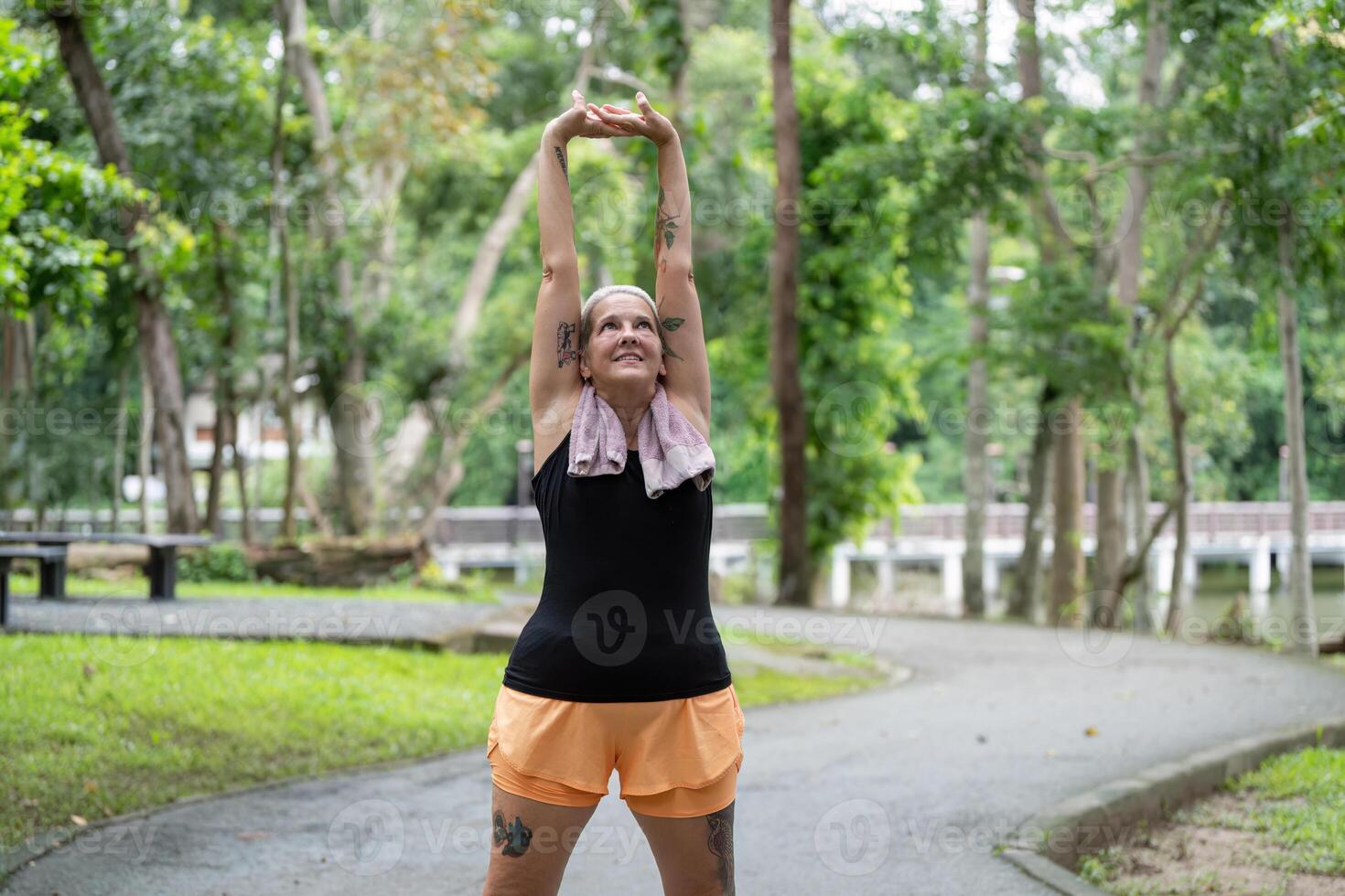 Elderly woman performing full body stretch in park photo