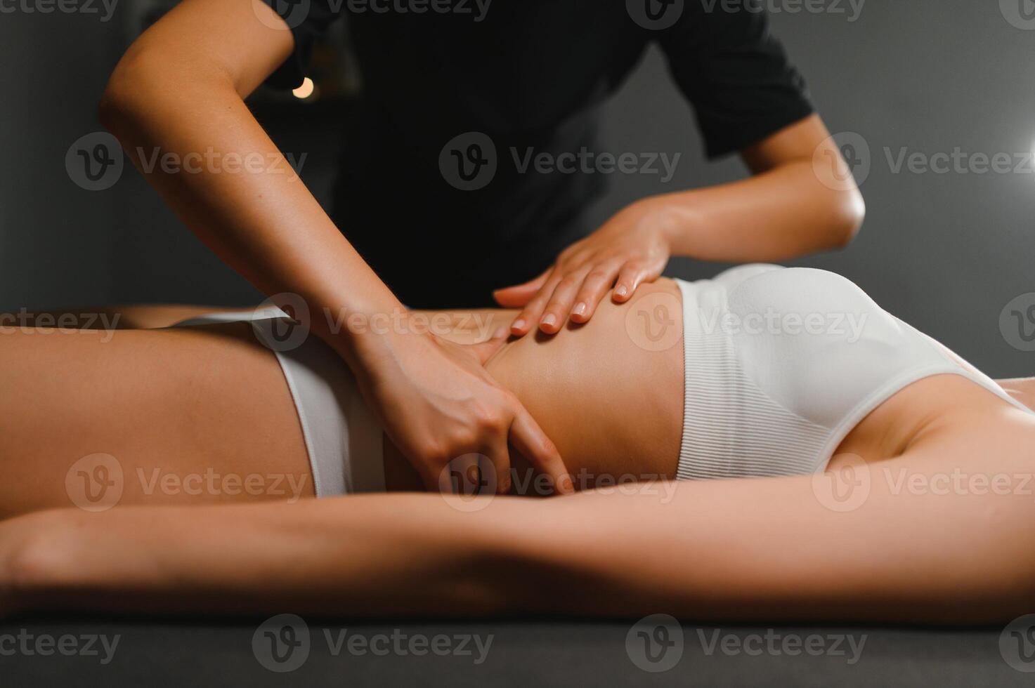 A masseuse woman doing an oil massage to woman on the stomach photo