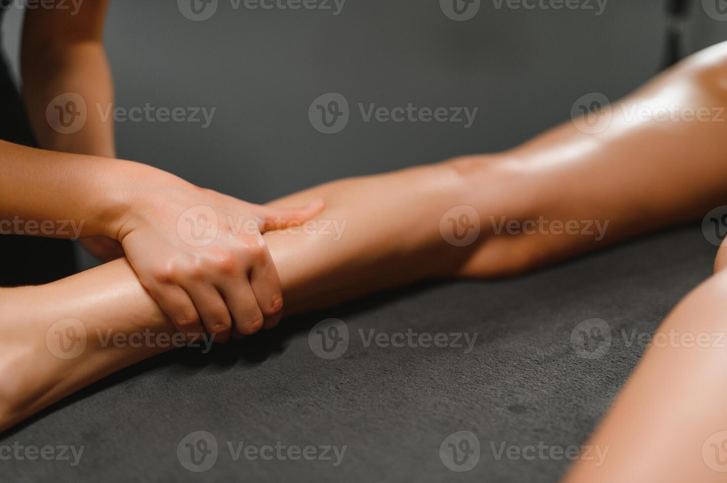 Beauty treatments for weight lost. Cropped shot of therapist or masseur doing lymphatic drainage or anti cellulite massage on legs for woman client lying at spa center photo