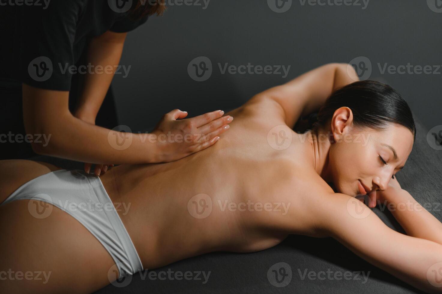 Body massage treatment. Woman having massage in the spa salon. Masseur working on his back photo