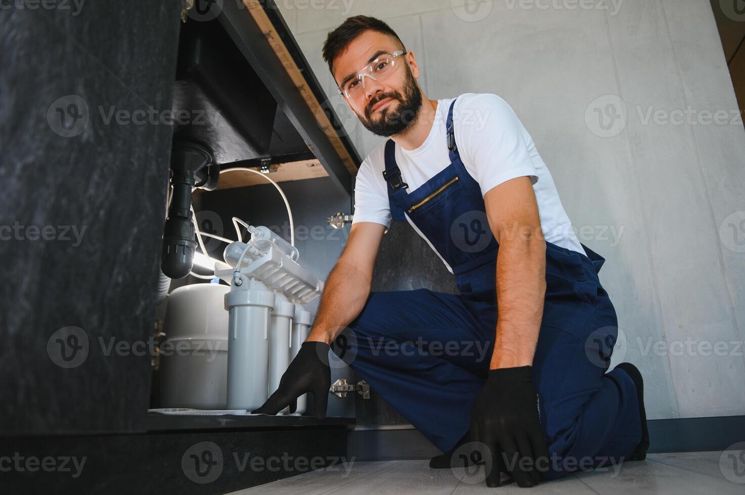 Plumber working install new cartridge for cold water filter in white kitchen photo