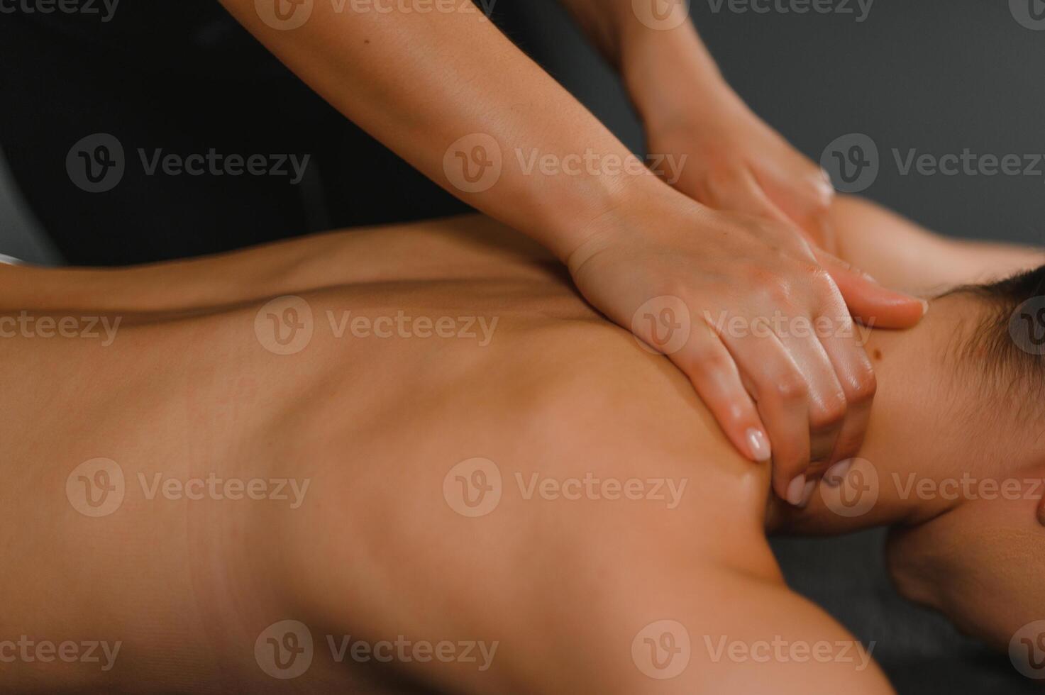 Masseur massaging back and shoulder blades of young woman lying on massage table. Concept of massage spa treatments photo