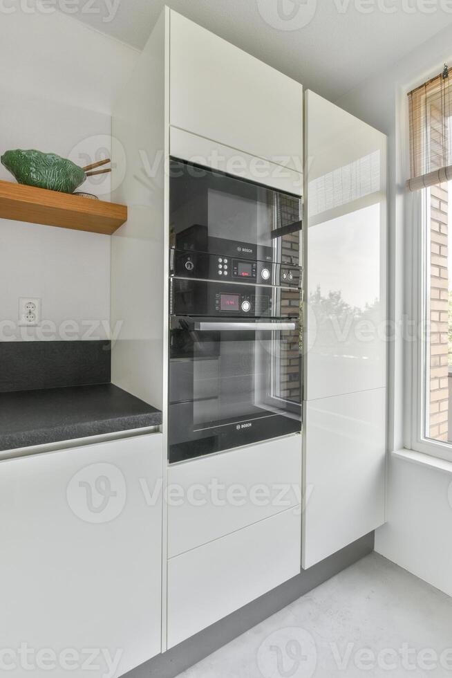 A kitchen with a large window and a white cabinet photo