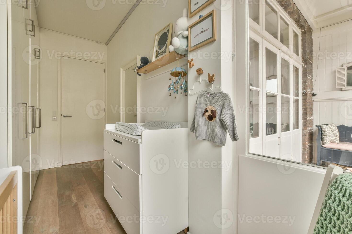 A small room with a white dresser and a wooden floor photo