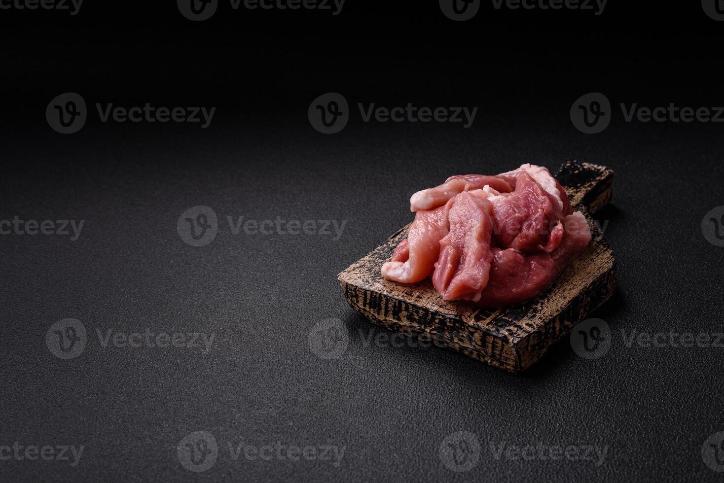 A pieces of raw fresh pork on a wooden cutting board with spices and herbs photo