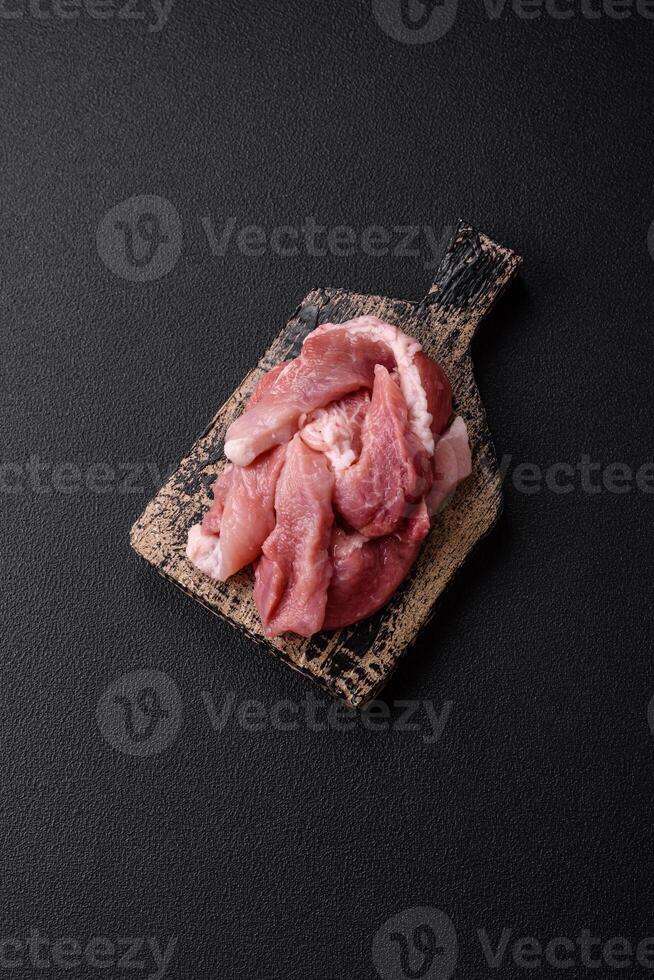A pieces of raw fresh pork on a wooden cutting board with spices and herbs photo