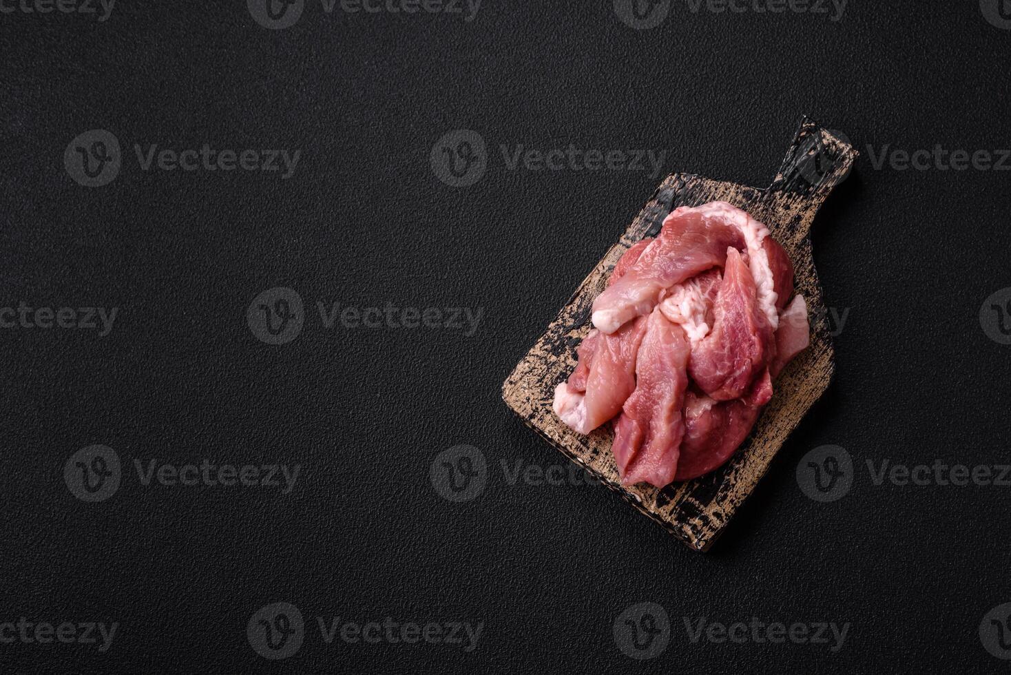 A pieces of raw fresh pork on a wooden cutting board with spices and herbs photo