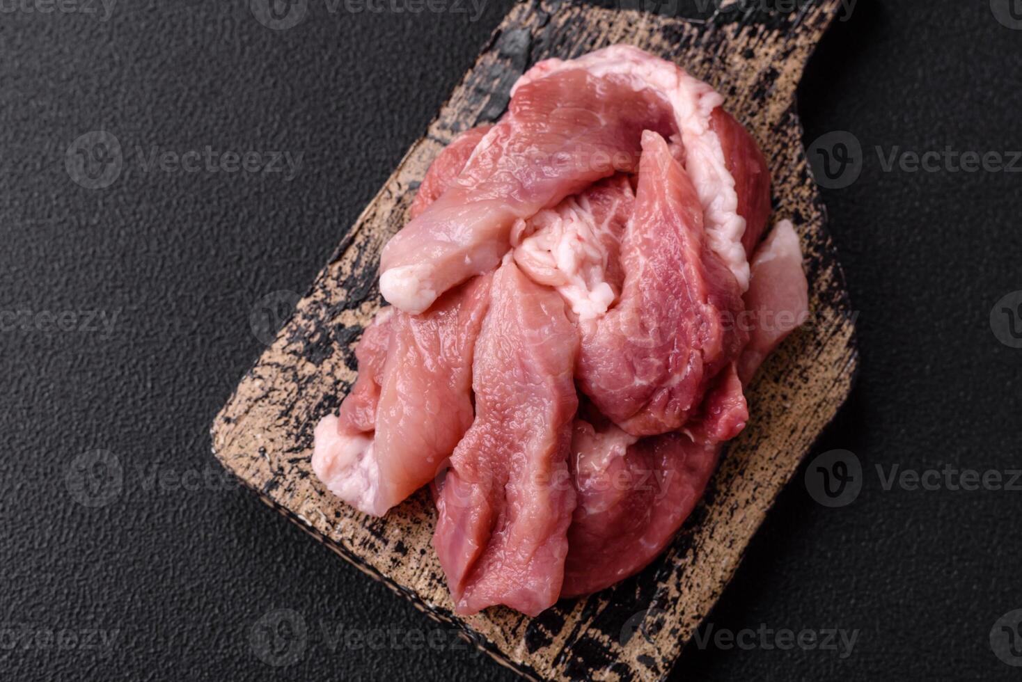 A pieces of raw fresh pork on a wooden cutting board with spices and herbs photo