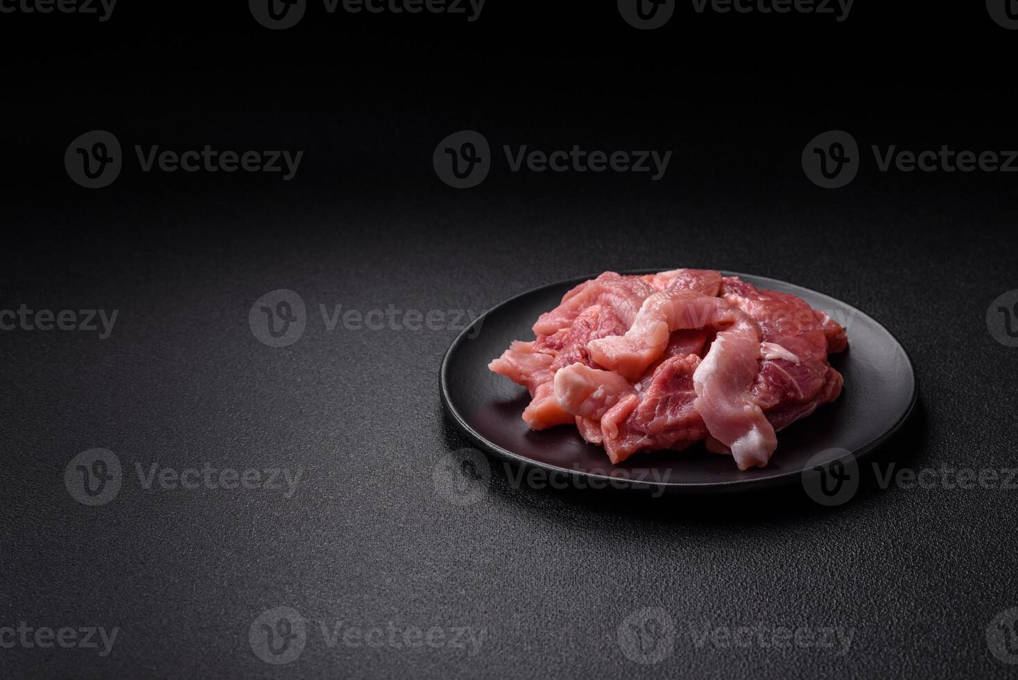 A pieces of raw fresh pork on a wooden cutting board with spices and herbs photo