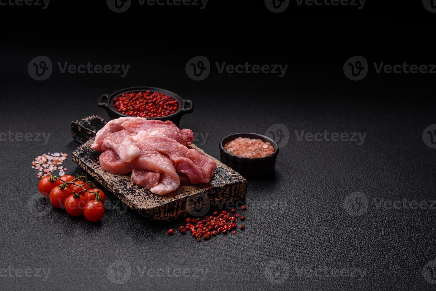 A pieces of raw fresh pork on a wooden cutting board with spices and herbs photo