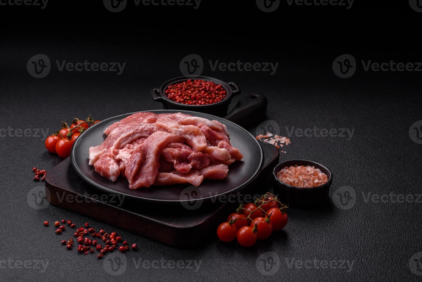 A pieces of raw fresh pork on a wooden cutting board with spices and herbs photo
