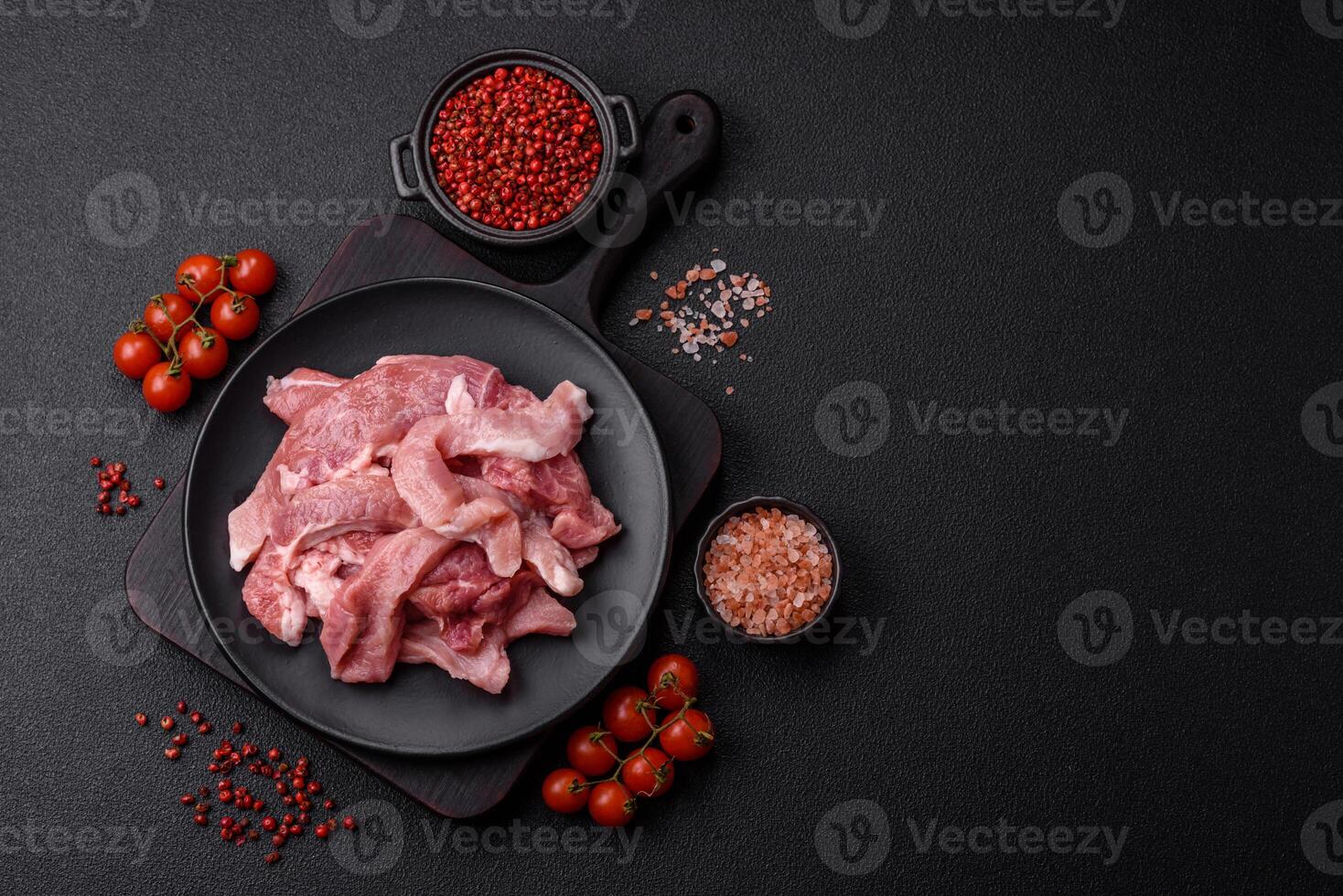 A pieces of raw fresh pork on a wooden cutting board with spices and herbs photo