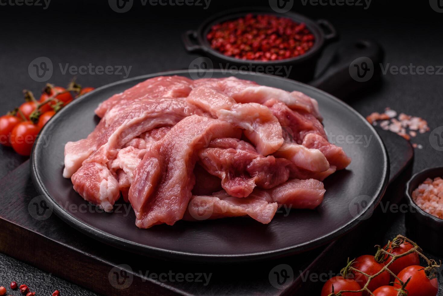 A pieces of raw fresh pork on a wooden cutting board with spices and herbs photo