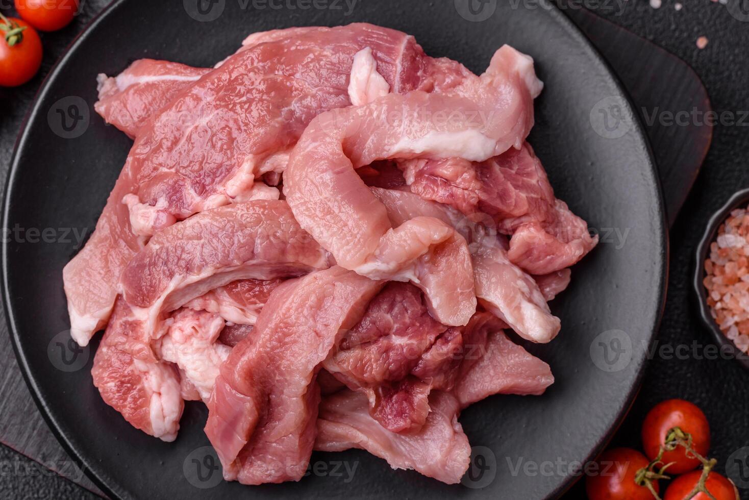 A pieces of raw fresh pork on a wooden cutting board with spices and herbs photo
